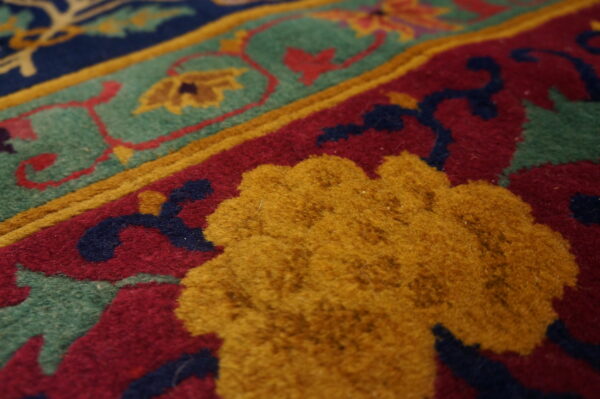 Detail of a high-pile rug with raised yellow, deep red, teal, and navy patterned sections.