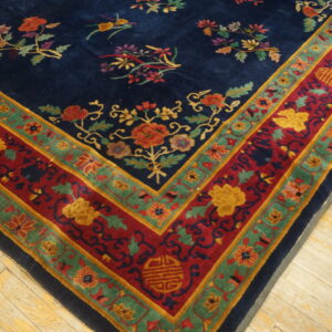 A detailed blue rug with multicolored floral sprays and a wide red and green border rests on pale wood.