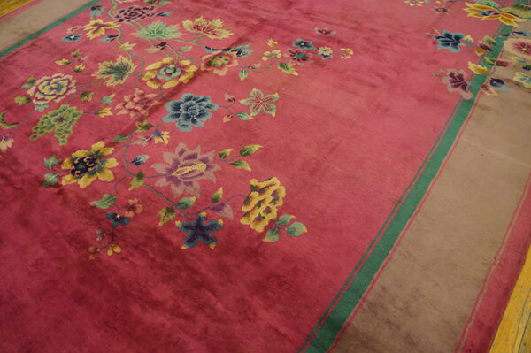 Magenta rug featuring blue, yellow, and green floral designs and a broad tan border with green stripes.