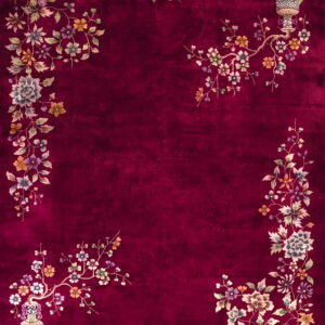A deep maroon rug with an elaborate multicolored floral border and corner motifs, including vases and lanterns.