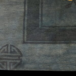 Detail view of a deep blue rug showing a dark geometric corner symbol and thick border.