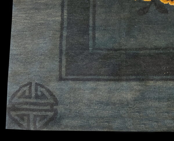 Detail view of a deep blue rug showing a dark geometric corner symbol and thick border.