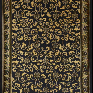 Black rug with an all-over golden floral vine pattern and a geometric Greek key border.
