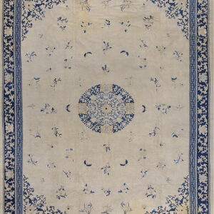 Ivory rug with scattered blue floral motifs, a central medallion, and a wide navy border.