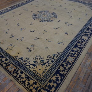 Large beige rug with a dark navy border and central medallion rests on rustic wood floors.