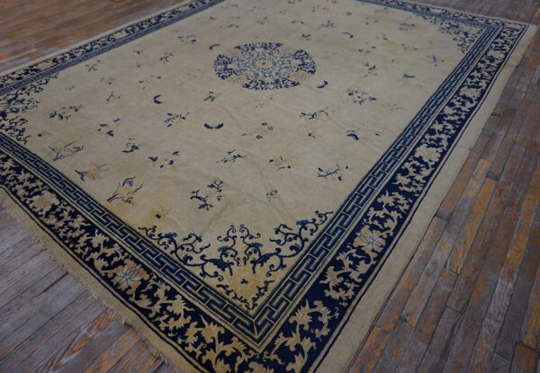 Large beige rug with a dark navy border and central medallion rests on rustic wood floors.