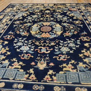 Ornate navy rug featuring beige, blue, and coral floral and geometric patterns on hardwood flooring.