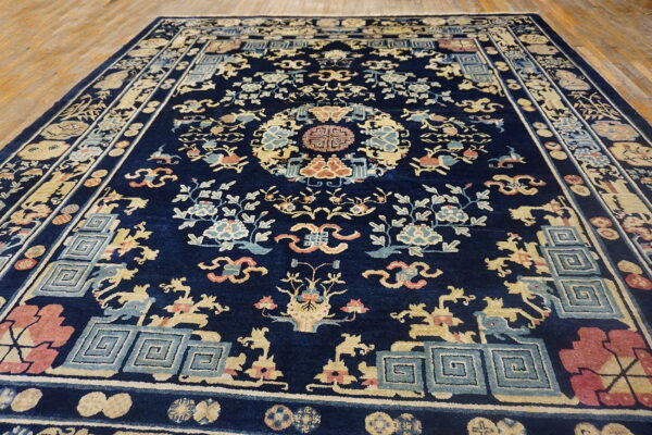 Ornate navy rug featuring beige, blue, and coral floral and geometric patterns on hardwood flooring.