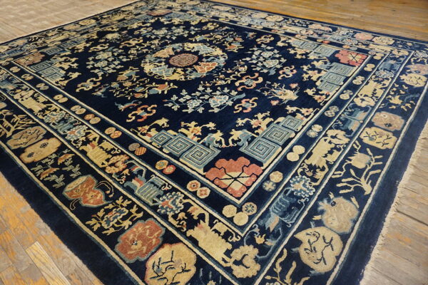 Ornate navy rug with gold and coral designs lies on distressed natural wood plank flooring.