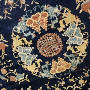 Navy blue rug featuring a complex pattern of gold, rust, and dusty blue stylized medallions and florals.