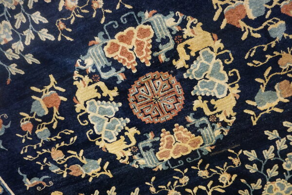 Navy blue rug featuring a complex pattern of gold, rust, and dusty blue stylized medallions and florals.