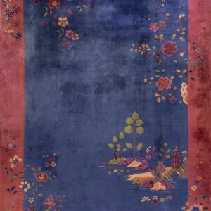 Blue rug with a wide rose-colored border, featuring floral sprays and a detailed landscape design.