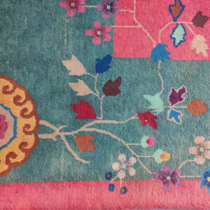Teal and pink rug detail with colorful stylized floral and vine patterns in gold, purple, and blue.