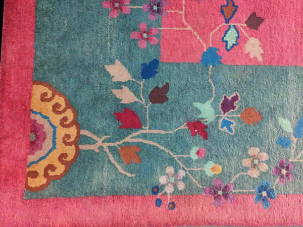 Teal and pink rug detail with colorful stylized floral and vine patterns in gold, purple, and blue.