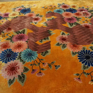 High-pile saffron rug displaying large blue, pink, and yellow floral bouquets alongside brown geometric patterns.