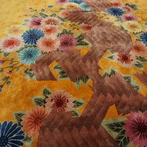 Yellow rug with sculpted brown pattern and large pink, blue, and coral floral motifs.