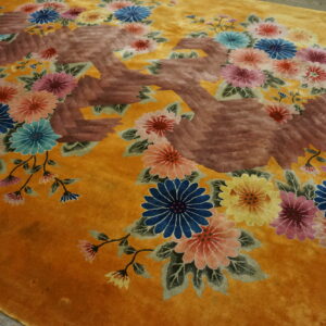 Golden yellow high-pile rug displaying carved multicolored floral clusters and a large reddish-brown abstract motif.