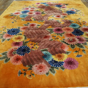 Mustard yellow rug featuring a central brown vine with multicolored floral sprays on a plank wood floor.