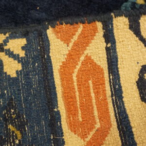 Detail shot of a rug featuring high indigo pile next to a rust and tan flatweave geometric border.
