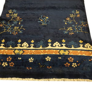 Navy blue plush rug with stylized gold and rust floral vines and an elaborate patterned border.