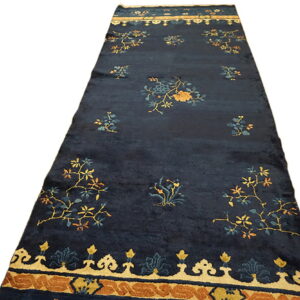 Navy blue runner rug with scattered gold and teal flowers and a wide tan and rust patterned border.