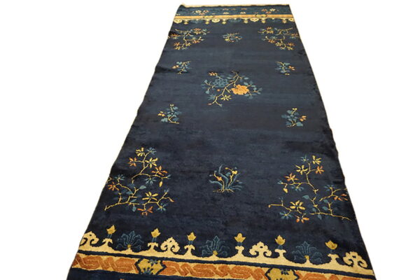Navy blue runner rug with scattered gold and teal flowers and a wide tan and rust patterned border.