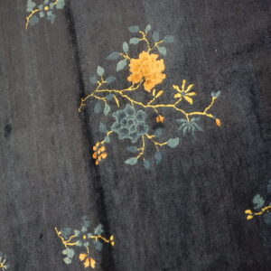 A dark blue rug with scattered gold and teal floral motifs rests on a light wood floor.