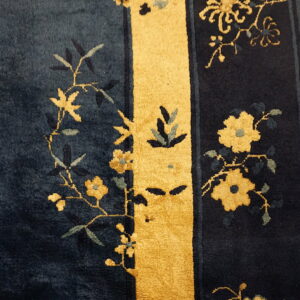 Deep blue high-pile rug detail featuring gold floral sprigs and a contrasting vertical yellow stripe.