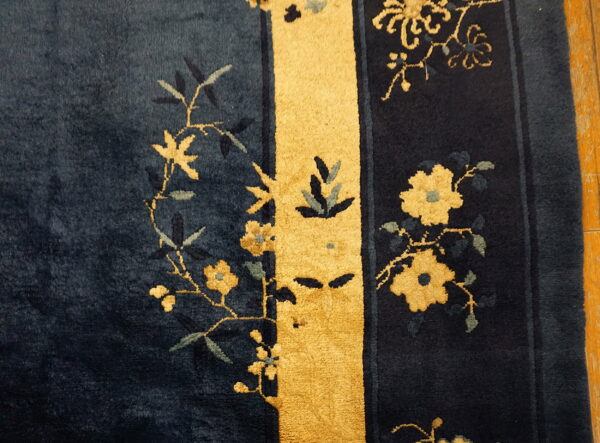 Deep blue high-pile rug detail featuring gold floral sprigs and a contrasting vertical yellow stripe.