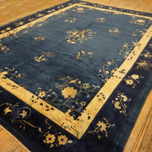 Large blue rug featuring traditional gold and navy floral patterns on a worn wooden plank floor.