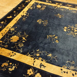 Blue high-pile rug with elaborate gold botanical patterns and borders shown on light wood planks.