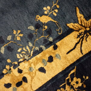 Plush navy and gold rug detail featuring a stylized bird, butterfly, and botanical design.