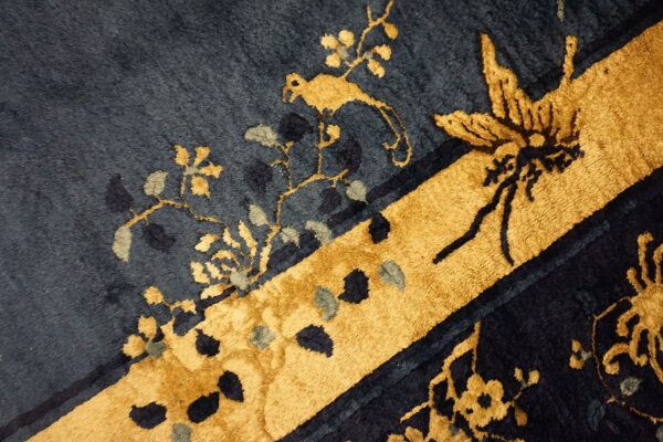 Plush navy and gold rug detail featuring a stylized bird, butterfly, and botanical design.