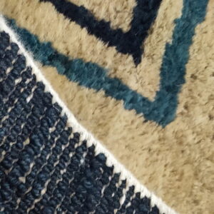 Rug detail showing a sharp division between woven flatweave and plush pile in navy, teal, and tan colors.