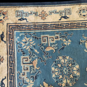 Detailed view of a teal rug with beige, navy, and brown intricate floral and geometric patterns.