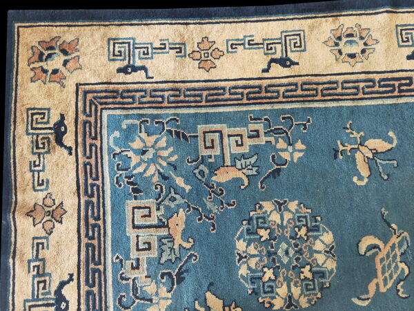 Detailed view of a teal rug with beige, navy, and brown intricate floral and geometric patterns.