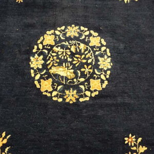Navy blue rug with a central circular golden medallion and scattered floral designs in the field.