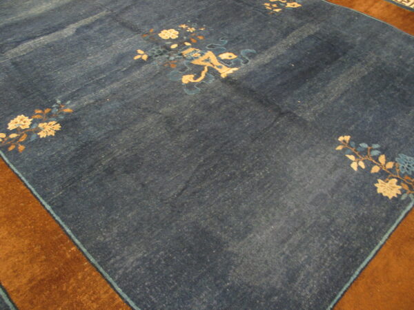 Deep blue rug with scattered cream and light blue floral patterns on a plush brown border.