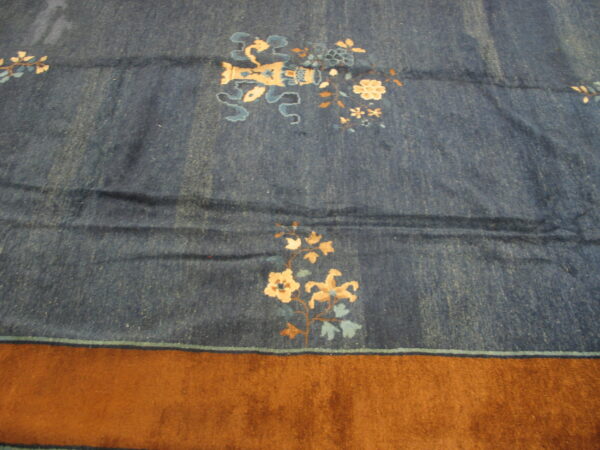 A dark blue rug featuring scattered tan and light blue floral patterns rests next to a brown carpet.