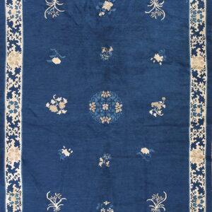Deep blue rug with scattered tan floral motifs and a wide, intricate beige and blue border pattern.