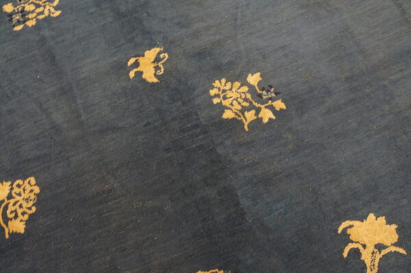 A dark blue rug displays scattered gold botanical and stylized animal silhouettes on a low-pile field.