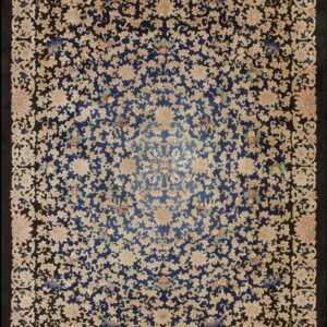 Ornate rug showing beige flowers and vines over a dark blue center and wide black borders.