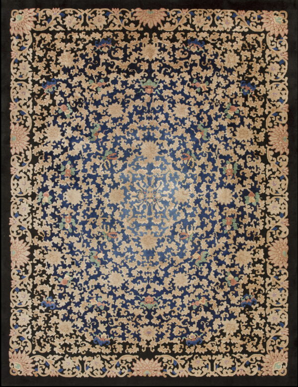 Ornate rug showing beige flowers and vines over a dark blue center and wide black borders.