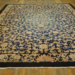 High-pile rug with dense cream floral patterns on a dark blue background and a solid black border on wood floors.