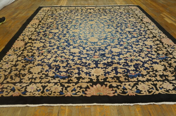 High-pile rug with dense cream floral patterns on a dark blue background and a solid black border on wood floors.