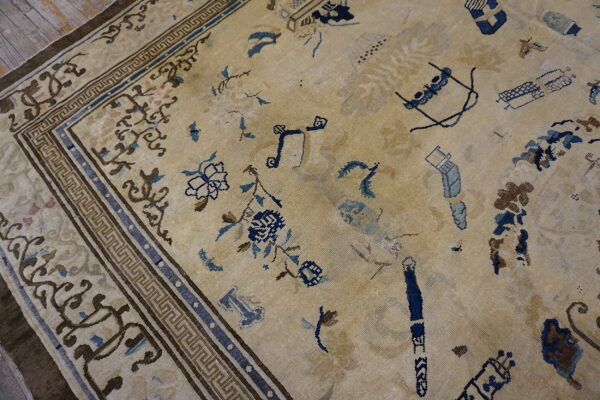 Low-pile beige rug with faded brown and blue abstract motifs resting on light wood flooring.