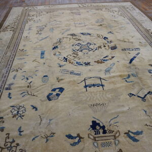 Light beige rug with scattered blue objects and patterns framed by geometric borders on dark wood.
