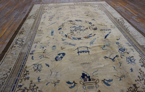 Light beige rug with scattered blue objects and patterns framed by geometric borders on dark wood.