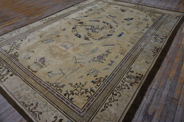 Faded beige rug with scattered blue and brown traditional motifs and a multi-layered border on rustic wood planks.