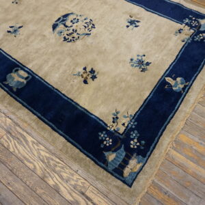 Beige rug with dark blue border and floral motifs lying on distressed wood planks.
